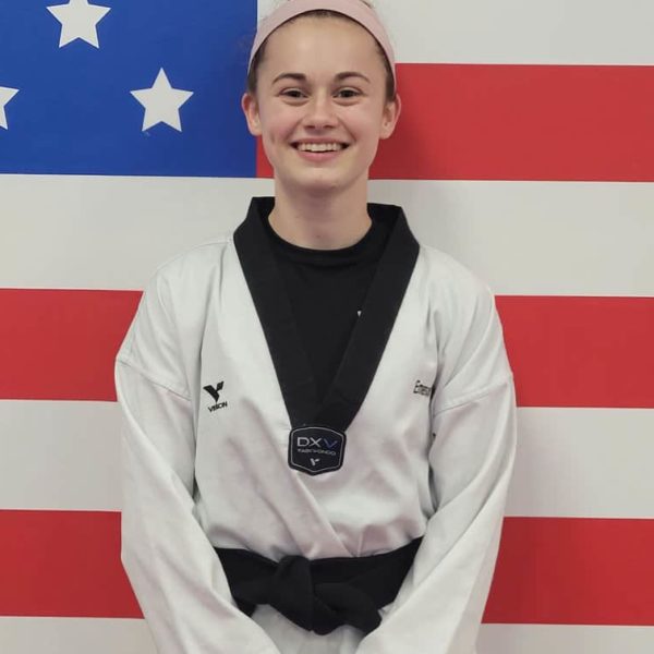 Caucasian teen girl wearing taekwondo dobak standing against a USA flag wall